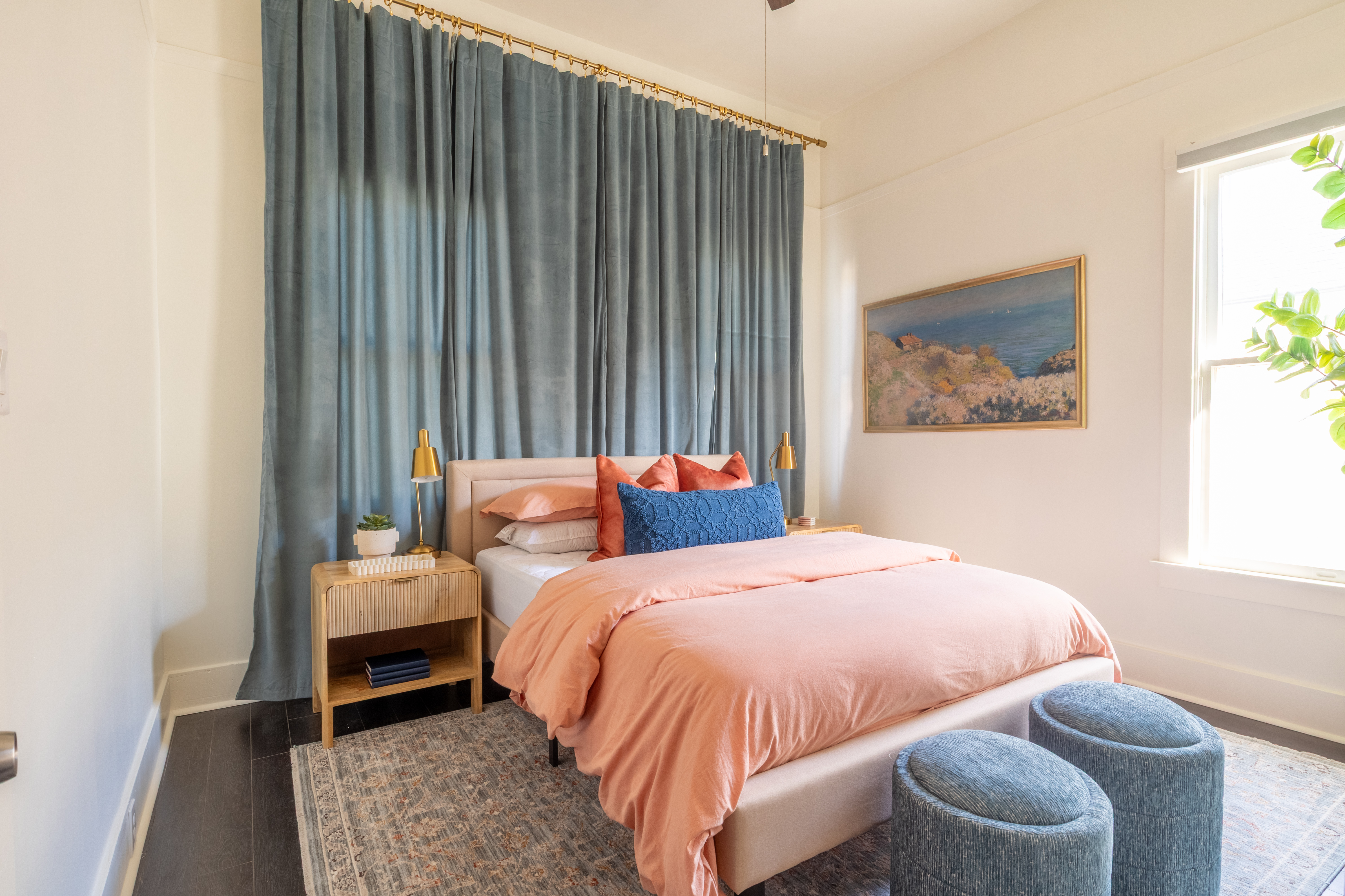 Primary bedroom with blue velvet drapes and coral duvet